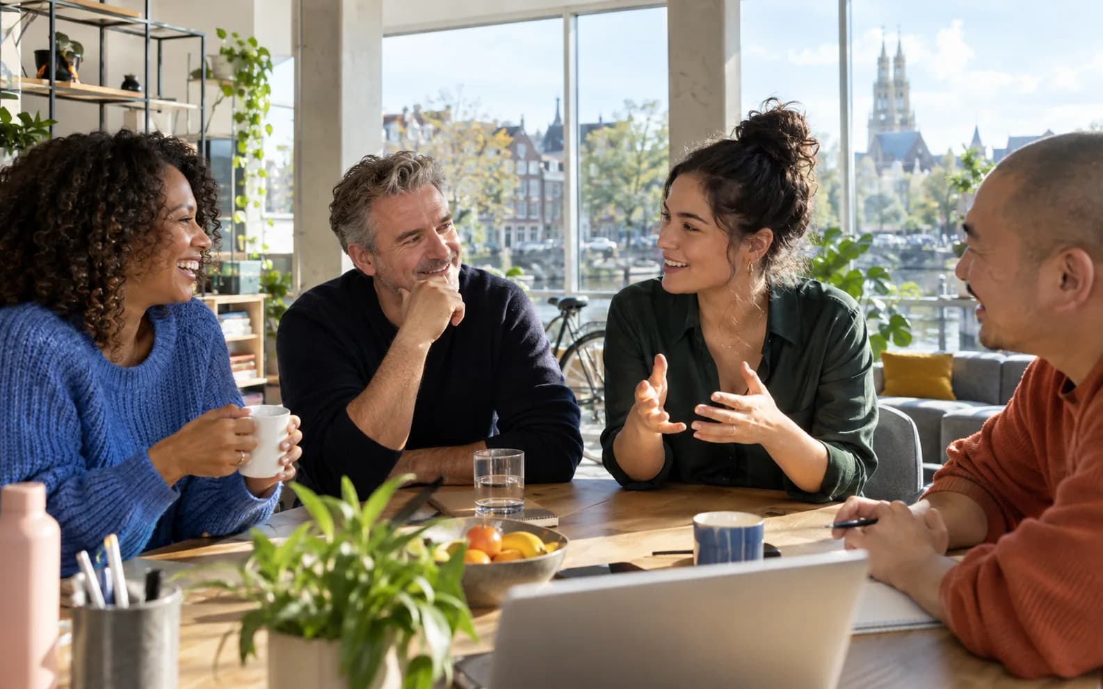 Vier professionals in gesprek in een zonnige Nederlandse werkruimte